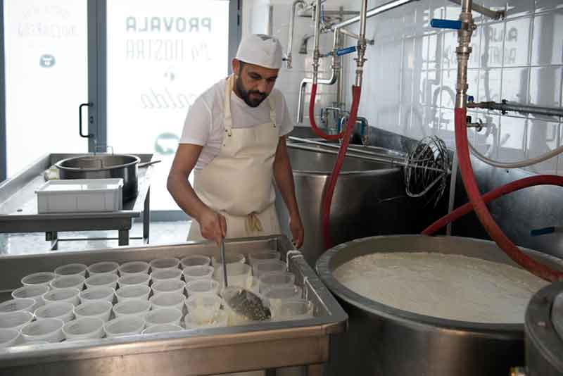 The mozzarella is stirred with a huge perforated spoon